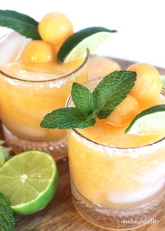 two glasses filled with lemonade, lime and mint garnish on a wooden tray