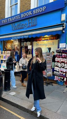 a woman is walking down the street in front of a book shop with people looking at books