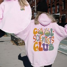 a woman wearing a pink sweatshirt with the words scientist's club printed on it