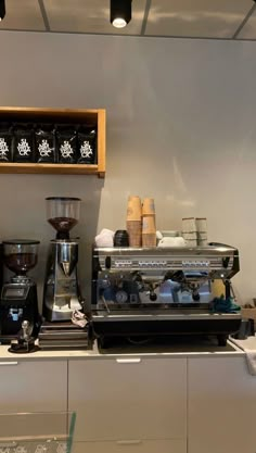 a coffee machine sitting on top of a counter next to a shelf filled with cups