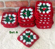 four crocheted coasters with holly decorations on them