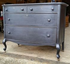 an old dresser is painted black and has knobs on the bottom drawer, which are not in use yet