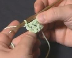 someone crocheting the end of a piece of yarn with a pair of hands