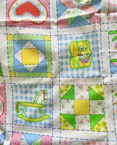 a close up of a quilt with different designs on it and the background is blue, green, pink, yellow and white