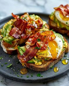 an open face sandwich with bacon, eggs and avocado