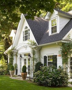 a white house with lots of windows and plants on the front lawn in front of it