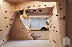 two people climbing up the side of a rock wall in a room filled with rocks