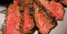 some steaks are being cooked on a grill with green dipping sauce in the background