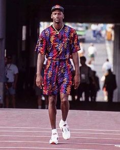 a man standing on top of a race track wearing a colorful shirt and short shorts