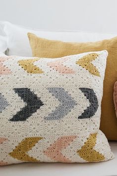 a crocheted pillow sitting on top of a bed next to a stuffed animal