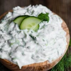 a wooden bowl filled with cucumber and sour cream