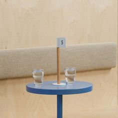 two shot glasses sitting on top of a blue table with a wooden stick in the middle