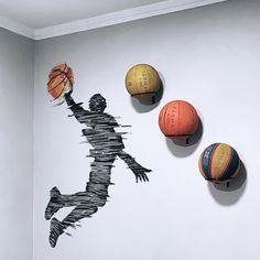 three basketballs are hanging on the wall next to a drawing of a man dunking a basketball