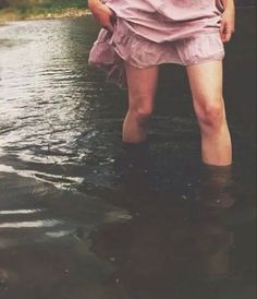 a woman is standing in the water with an umbrella