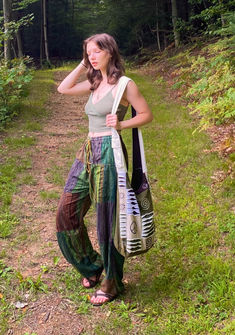 a woman is standing in the grass with her hand on her head and holding a bag