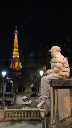 a man sitting on top of a stone bench next to the eiffel tower