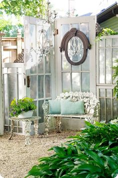 a bench sitting in front of a white building with windows and plants growing on it