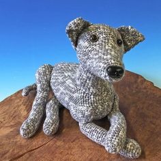 a knitted dog sitting on top of a wooden table next to a blue sky