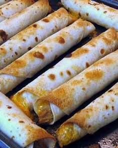 several burritos are being cooked in a pan on the stove with peppers and cheese