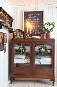 an old china cabinet is decorated with wreaths and greenery for the holiday season