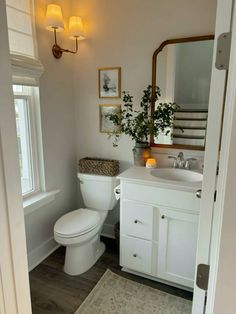 a white toilet sitting next to a sink in a bathroom under a mirror and lights