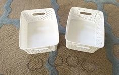 two white baskets sitting on top of a carpet next to pair of pairs of scissors