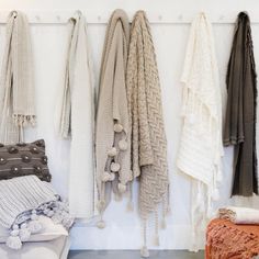 a bunch of sweaters hanging up on a wall next to pillows and blankets in a room