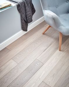 a grey chair sitting on top of a hard wood floor next to a white wall