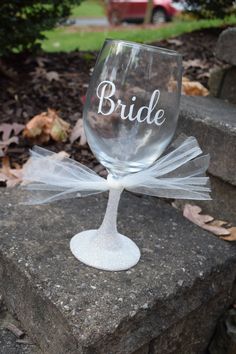 a wine glass with the word bride on it sitting on top of a stone wall