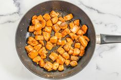 a pan filled with cooked food on top of a white marble countertop next to a spatula