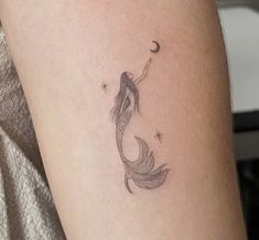 a woman's arm with a small fish tattoo on it