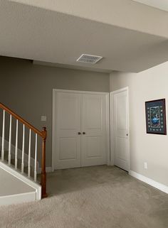 an empty room with two doors and a staircase leading to the second floor in front of it