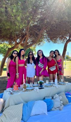 a group of women standing next to each other in front of a table with food on it