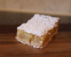 a piece of cake sitting on top of a wooden table covered in powdered sugar