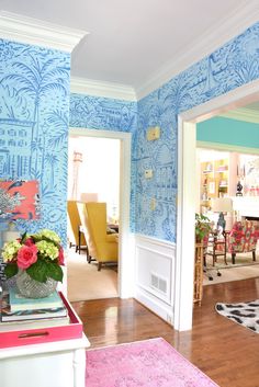 a living room with blue wallpaper and pink rugs on the hardwood flooring