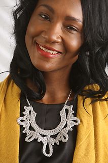 a smiling woman wearing a yellow jacket and black top with a necklace on her neck