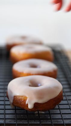 a row of glazed donuts sitting on top of a cooling rack