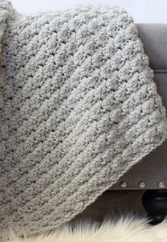 a crocheted blanket sitting on top of a couch next to a white rug