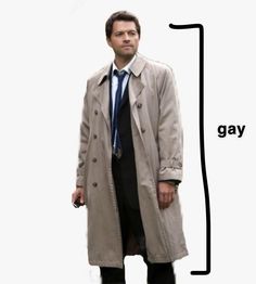 a man in a trench coat and tie standing next to a sign that says gay