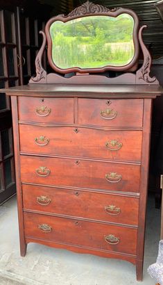 an old wooden dresser with a mirror on it's top and bottom drawer open