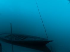 a boat floating on top of a body of water covered in fog and smog