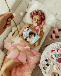 a woman laying on the floor next to a table with pink flowers and other decorations