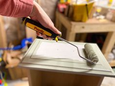 a person using a tool to cut paper on top of a table in a workshop