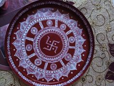 a red plate with white designs on it sitting on top of a table next to other items