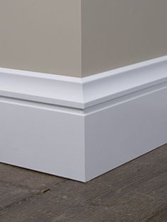 the corner of an empty room with wood flooring and white trim on the walls