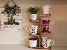 coffee cups and mugs are arranged on wooden shelves in front of a christmas sign