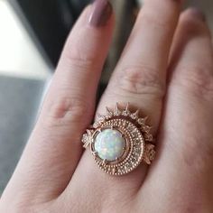 a close up of a person's hand wearing a ring with an opal