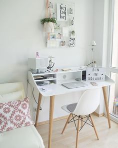 a white desk with a laptop computer on top of it next to a chair and window