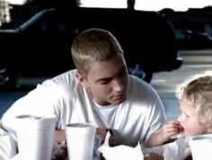 a man and child sitting at a table with milkshakes in front of them