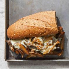 a close up of a sandwich in a pan on a metal tray with meat and cheese